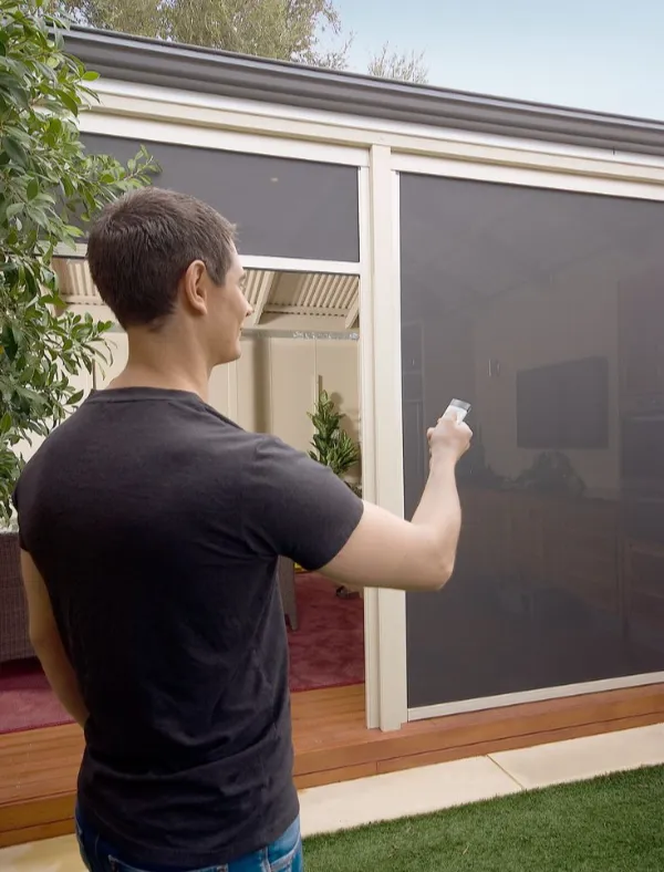Individual using a remote control to operate motorized blinds in a modern setting.